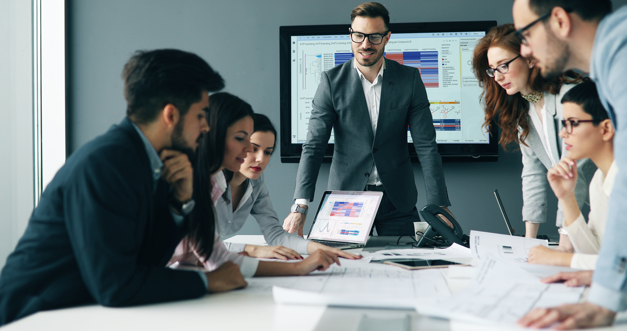 an end-to-end clinical solution brochure cover image, man in conference room standing in front of monitor and team around him