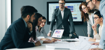 an end-to-end clinical solution brochure cover image, man in conference room standing in front of monitor and team around him